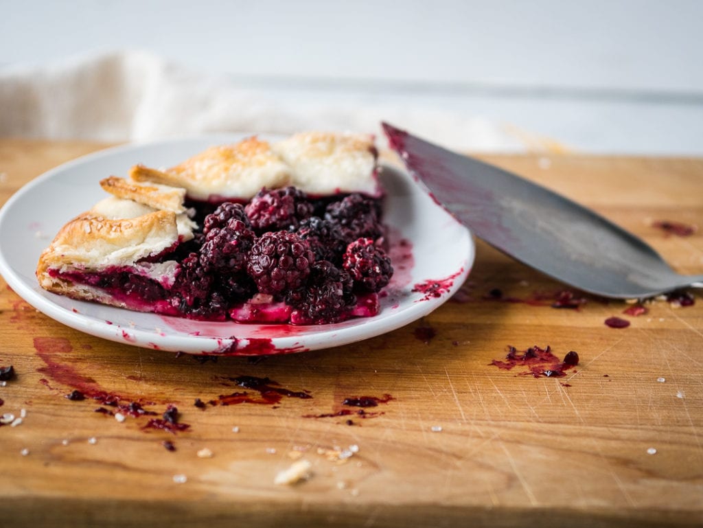 slice of blackberry galette on a plate with serve next to it