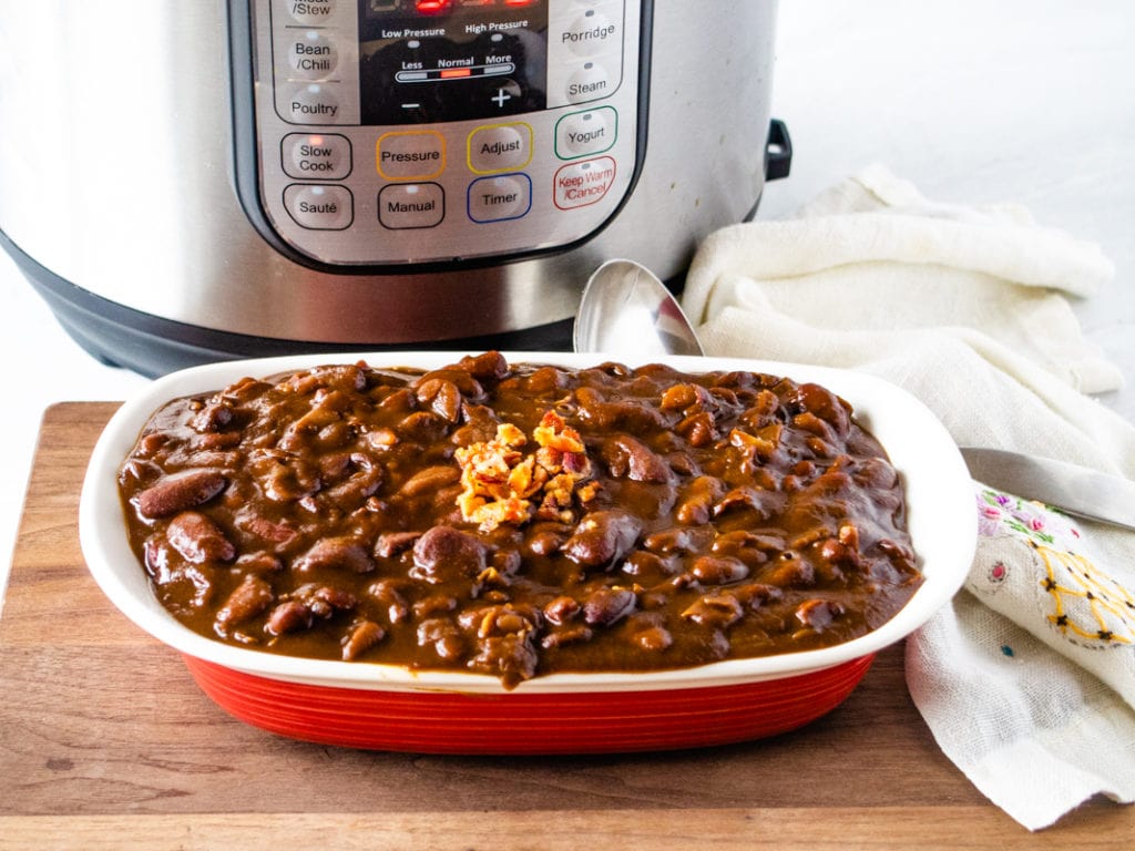 dish with baked beans topped with bacon in front of an Instant pot