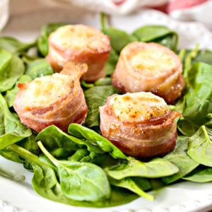 four scallops wrapped in bacon on a bed of spinach