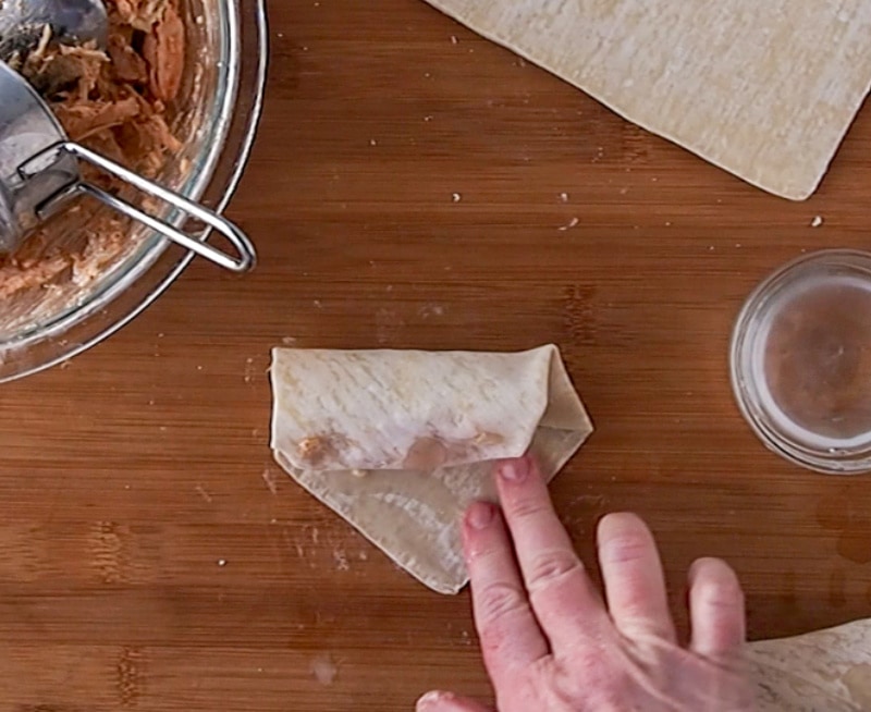 adding water to the edge of the egg roll wrapper