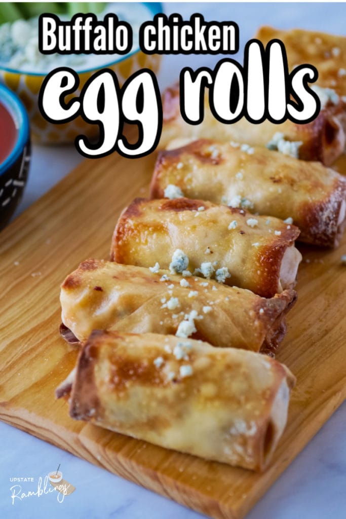 egg rolls topped with blue cheese on a wooden cutting board
