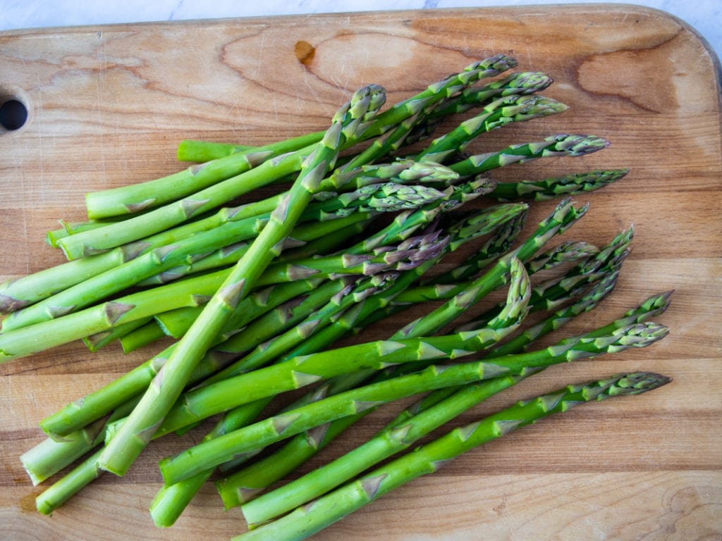 uncooked asparagus on a wooden cutting board