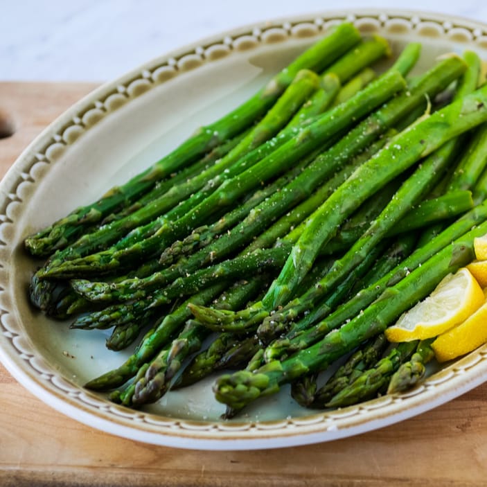 plate of sous vide asparagus with lemon wedges