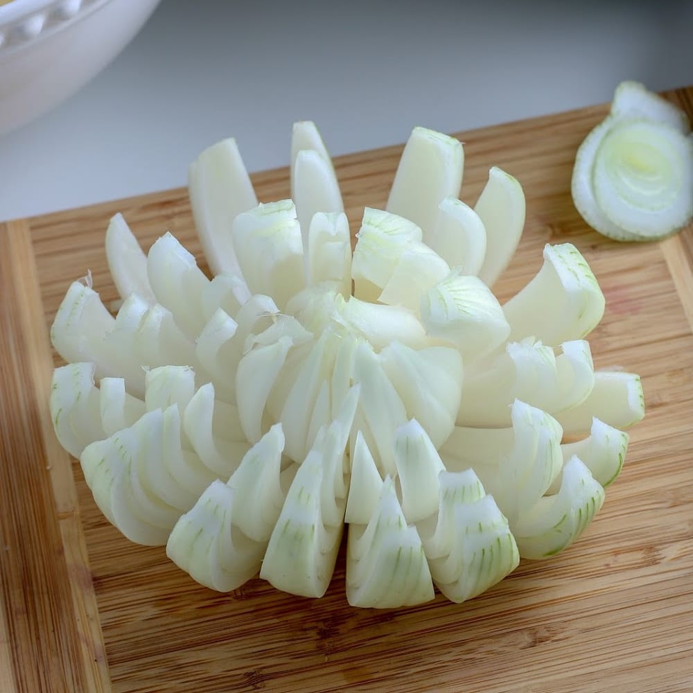 Sliced onions on a cutting board next to a bowl - air fryer.