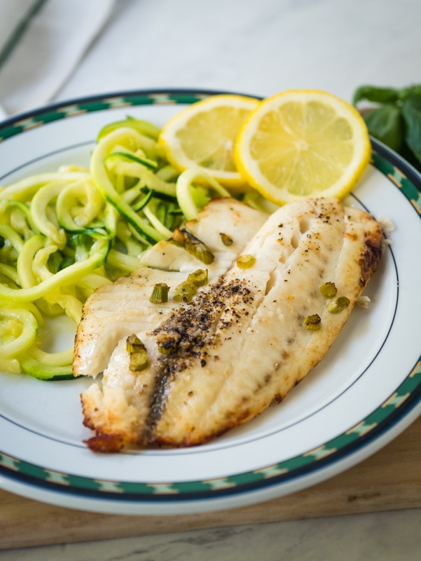 tilapia on a plate with lemon and squash