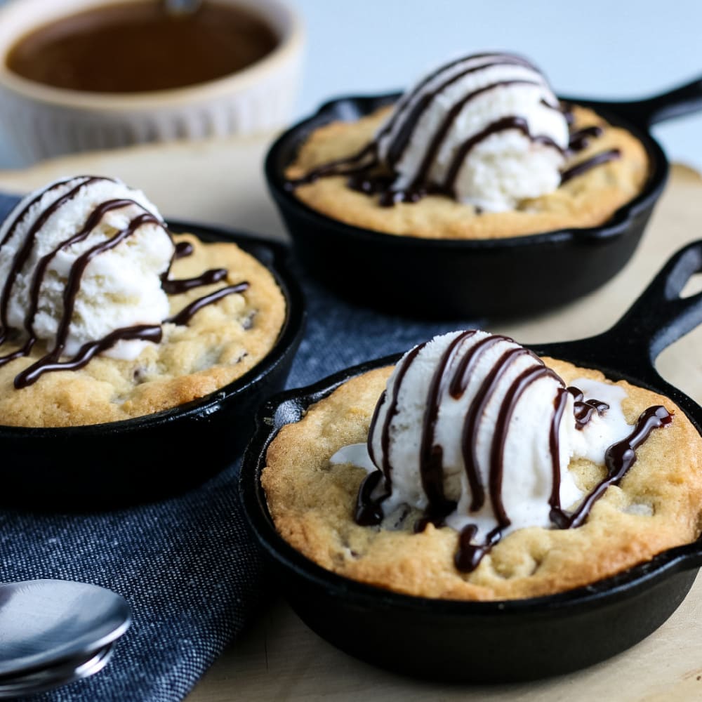 mini chocolate chip cookie skillets topped with ice cream in close up
