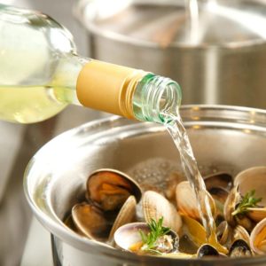 pouring wine into a pot of clams