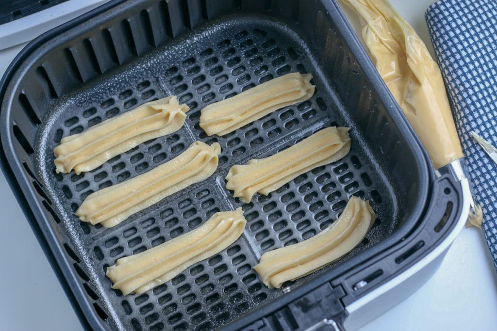 uncooked churros in air fryer basket