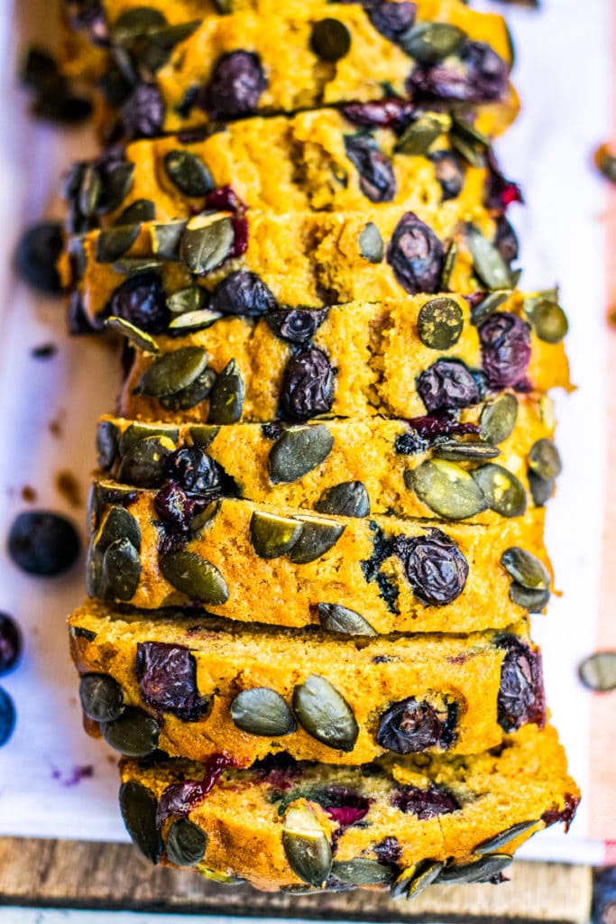 closeup of the top of pumpkin bread topped with blueberries and pumpkin seeds
