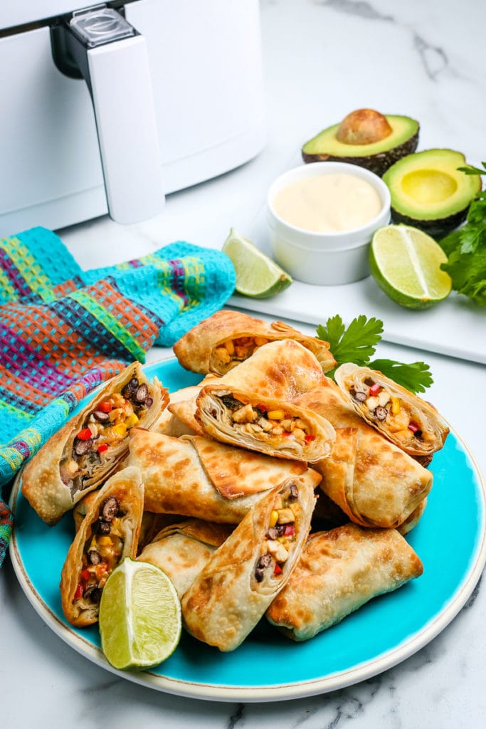 egg rolls on a plate in front of the air fryer