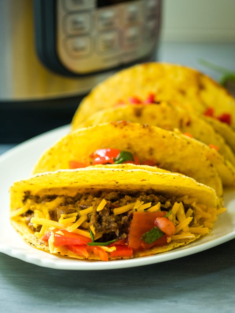 tacos on a plate in front of the Instant Pot