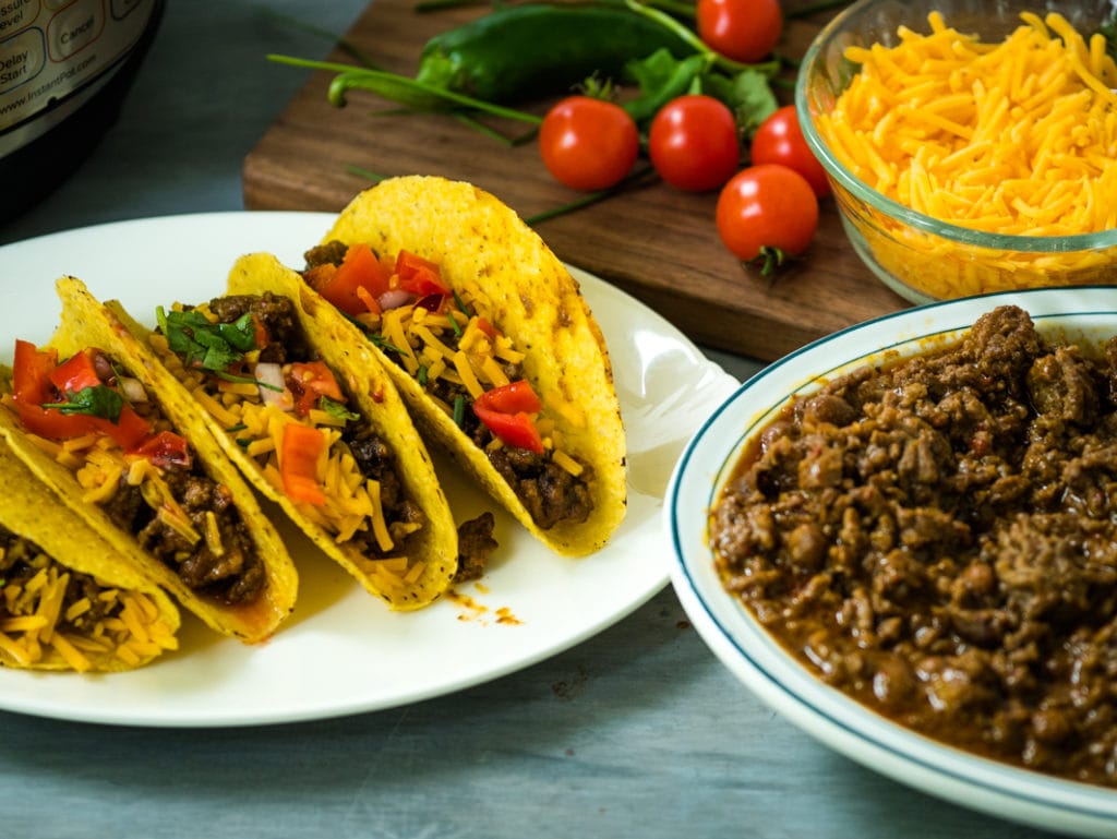 tacos on a plate with big bowl of taco meat