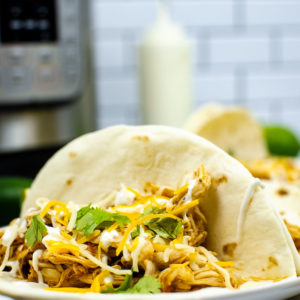 Instant pot chicken taco on a plate with presure cooker in background