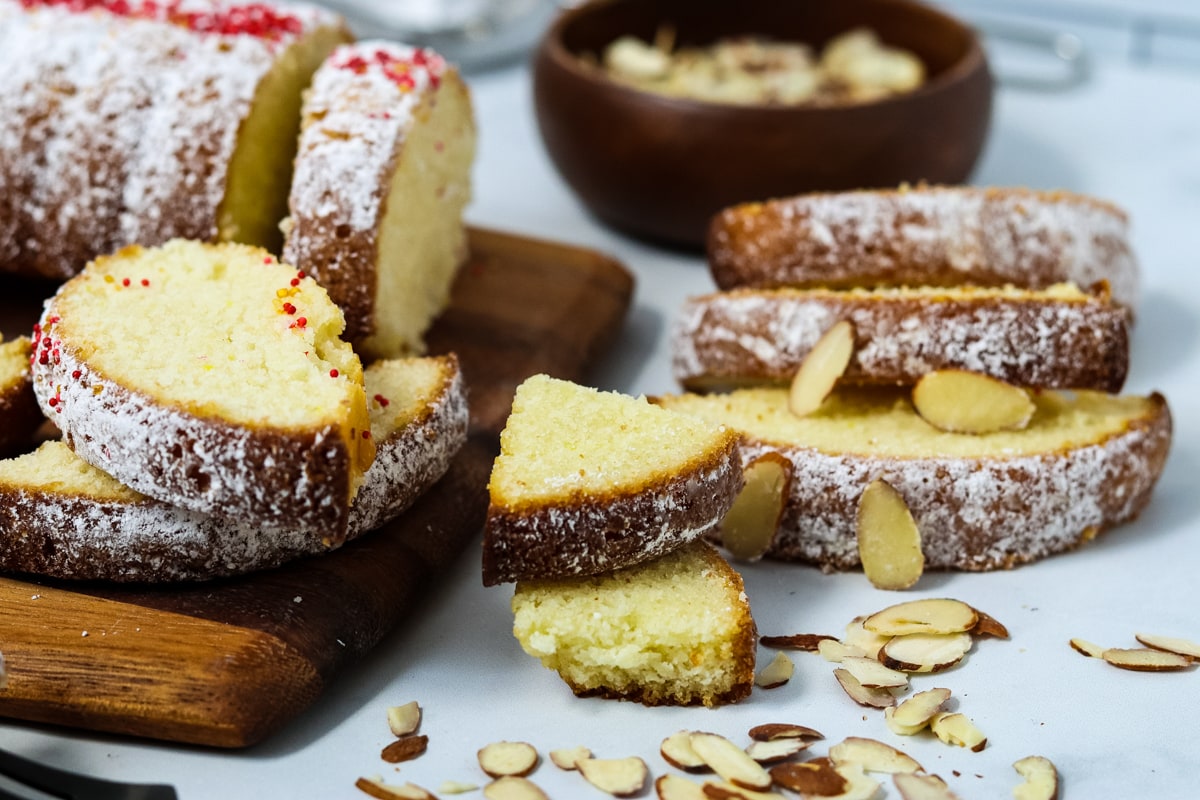 Slices of Swedish almond cake dusted with powdered sugar and topped with almonds.