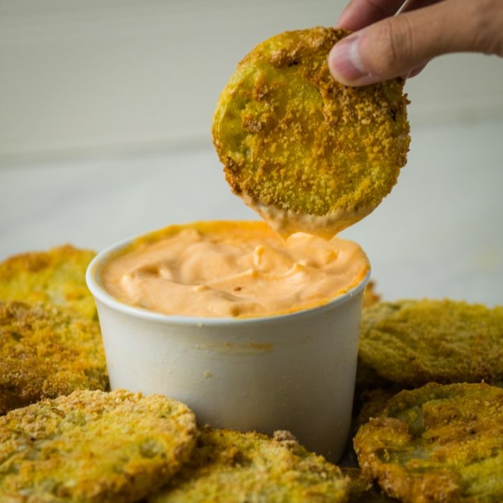 dipping a fried green tomato in sriracha mayonnaise