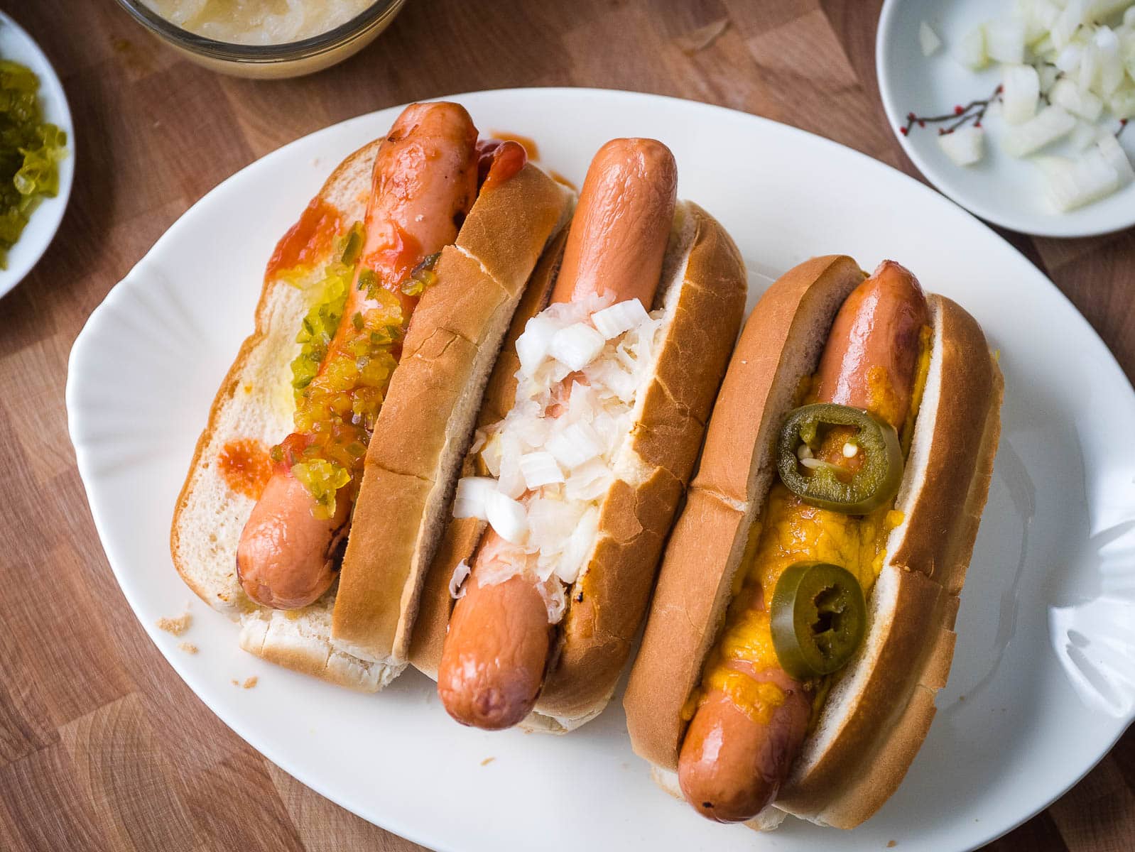 Three air fryer hot dogs in buns with toppings.