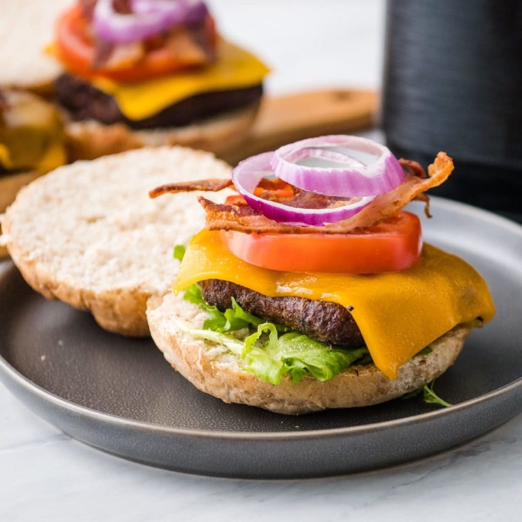 air fryer burger topped with cheese, tomato, bacon and more