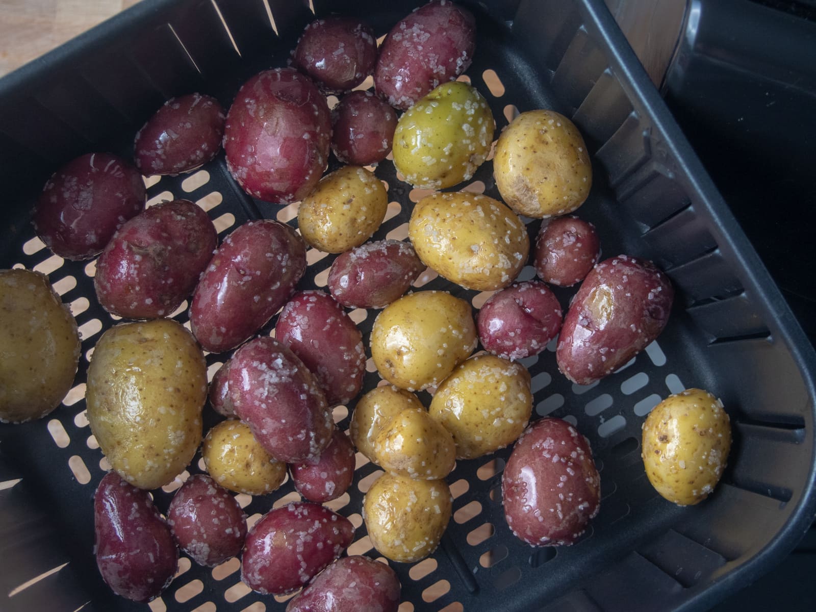 Top view of a plate of yellow and purple baby potatoes with salt.