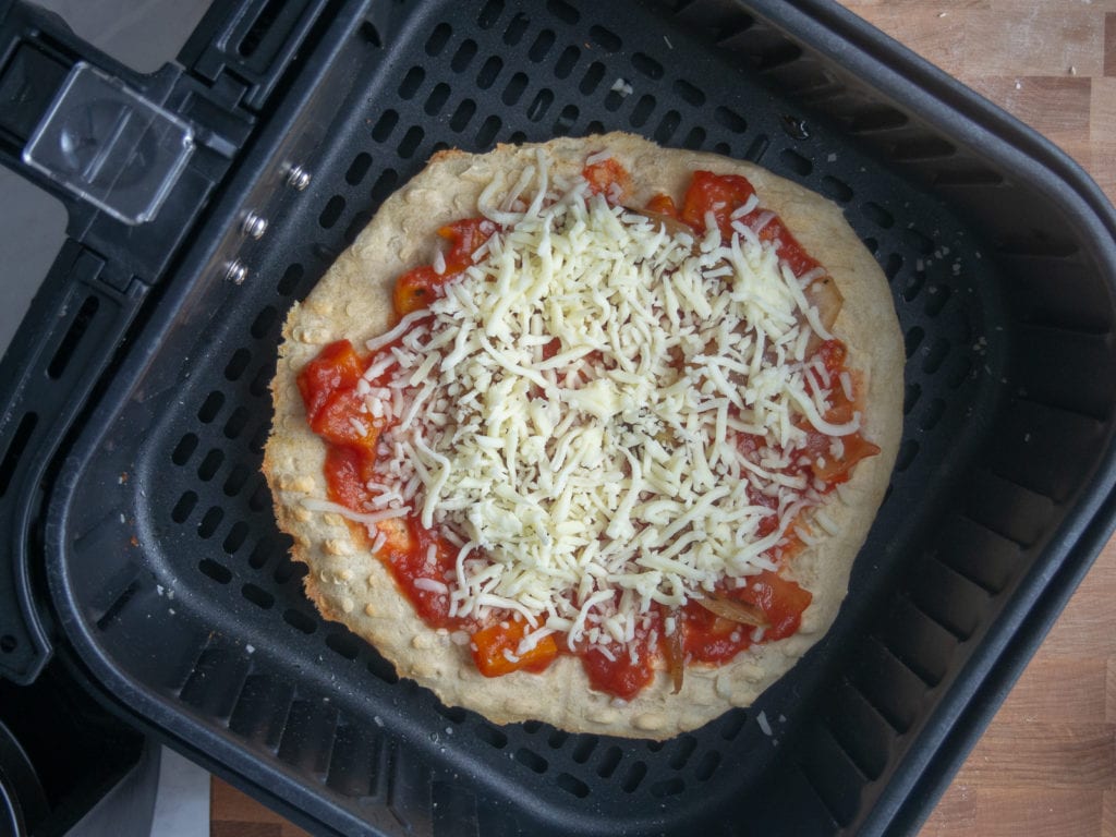pizza in air fryer basket before cheese melts