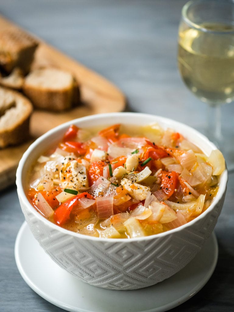 fish stew with bread and wine in the background