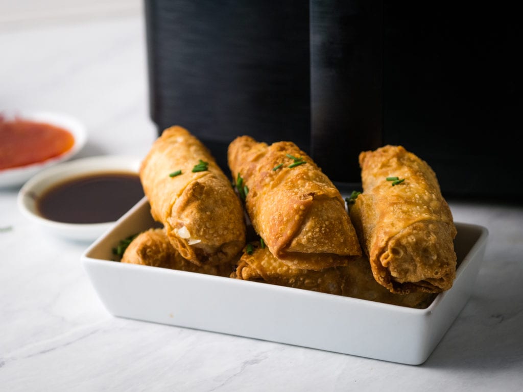 cooked egg rolls in front of air fryer
