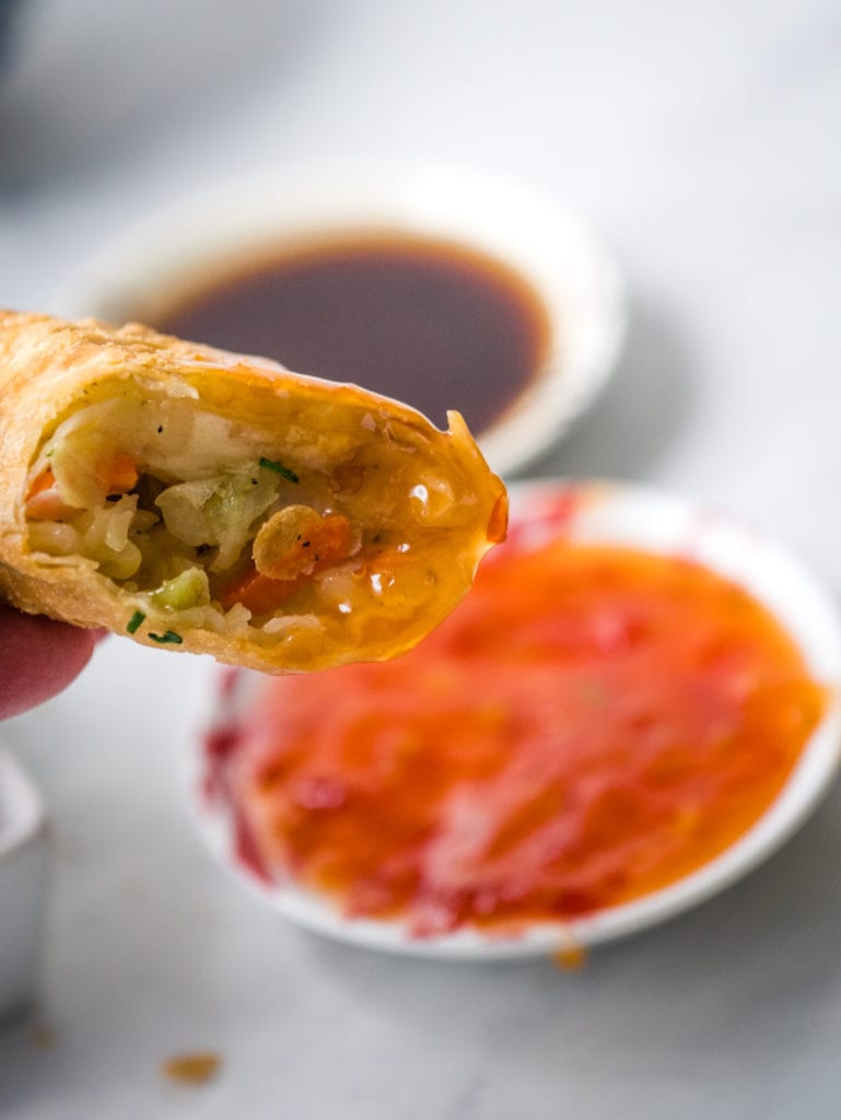 dipping egg roll in sweet and sour sauce