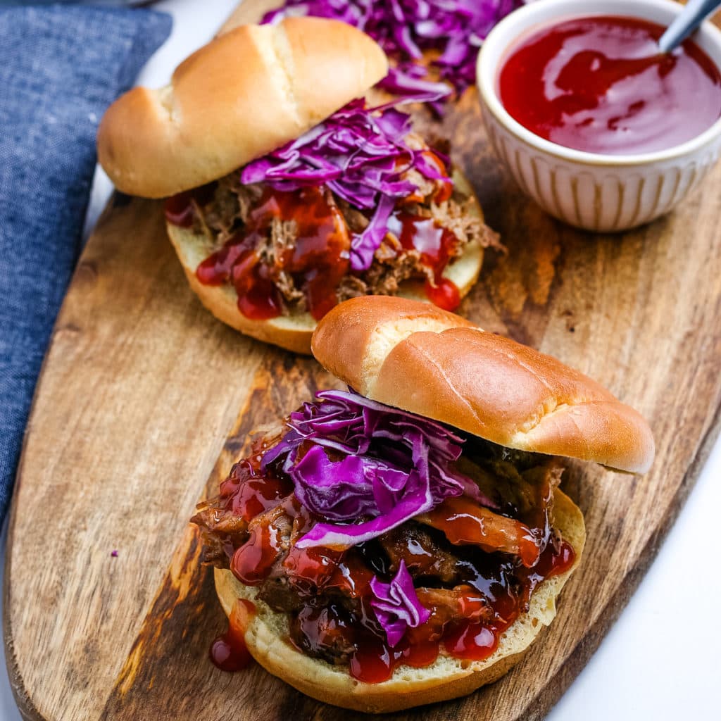 Instant Pot pulled pork sliders on a wooden cutting board
