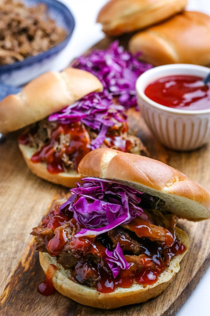 Instant pot pulled pork sliders on a wooden cutting board.