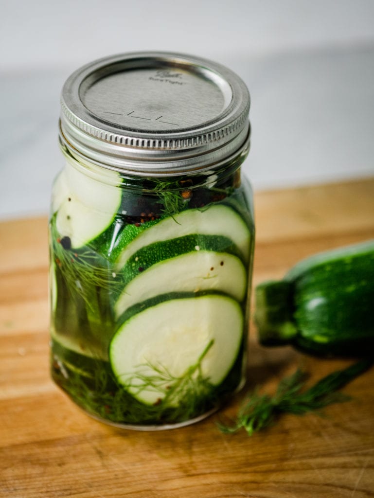 jar of zucchini pickles on a cutting board