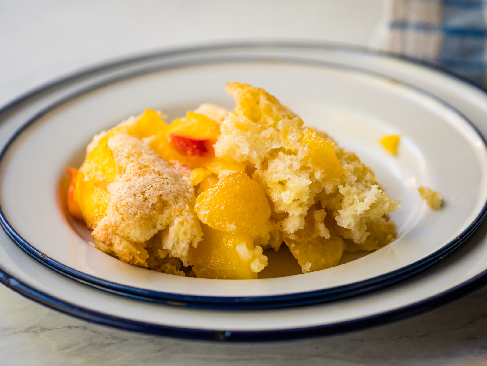 Plate with peach cobbler and a blue napkin.