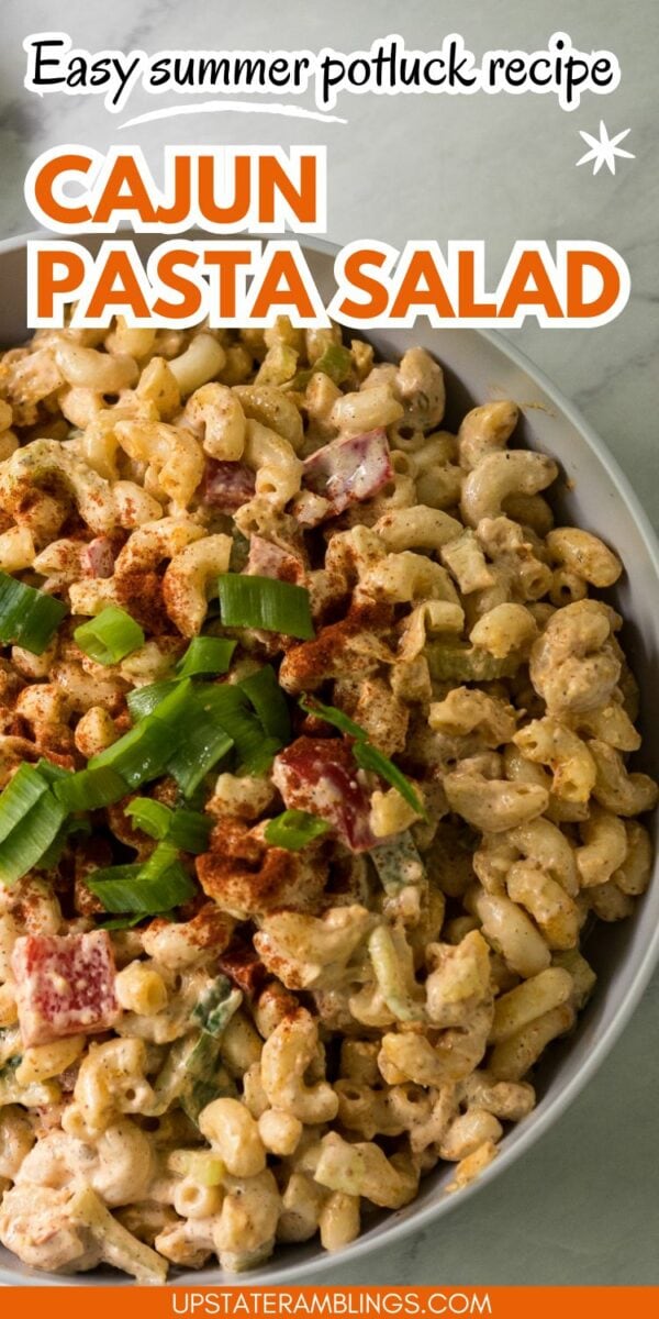 A bowl of Cajun pasta salad garnished with green onions. The image features text: "Easy summer potluck recipe: Cajun Pasta Salad." At the bottom, the website "upstateramblings.com" is mentioned. Savor this delicious and easy-to-make dish at your next gathering!