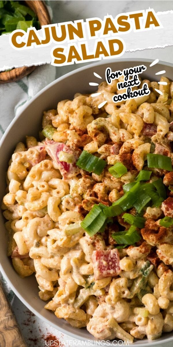 A bowl of creamy Cajun pasta salad topped with sliced green onions and paprika. Text on the image reads, "Cajun Pasta Salad for your next cookout." This dish is perfect for adding a flavorful twist to your summer gathering!