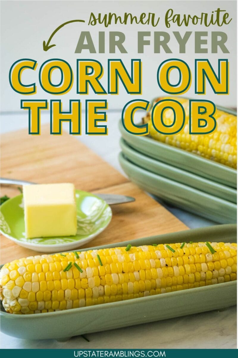 An air fryer with corn on the cob, garnished with chives. A dish with a slice of butter is nearby. The image text reads, "Summer favorite: Air Fryer Corn on the Cob." Enjoy this delightful air fryer corn on the cob!