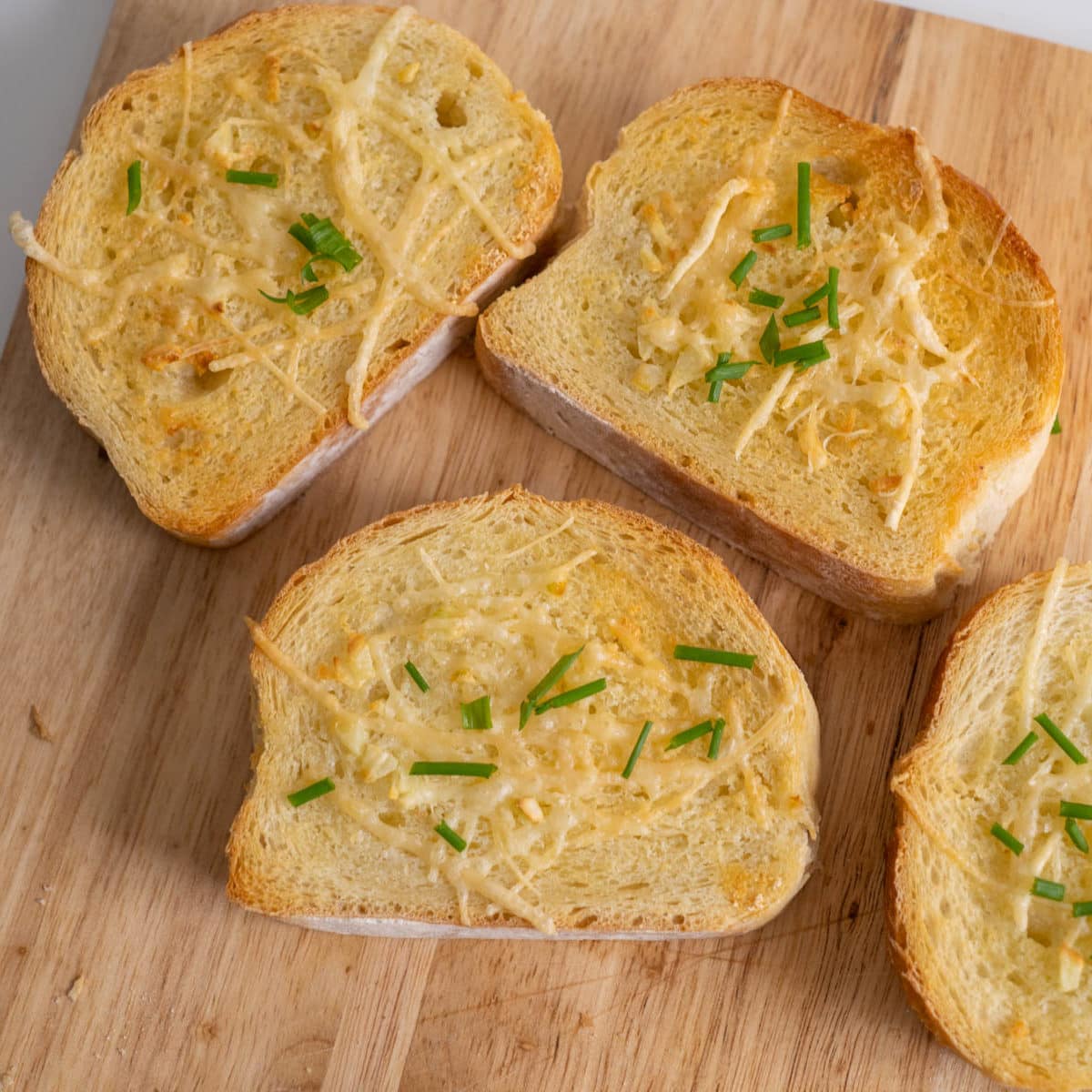 Top view of garlic bread with butter, garlic, Parmesan cheese and chives.