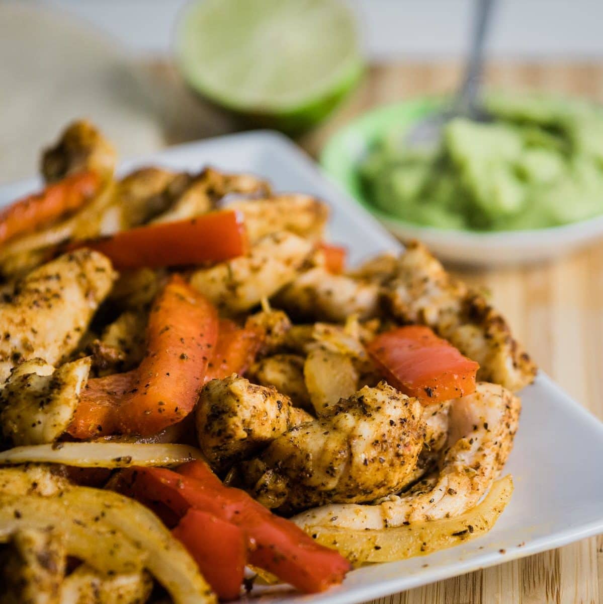 Plate of chicken fajitas with chicken, red bell peppers and onion.