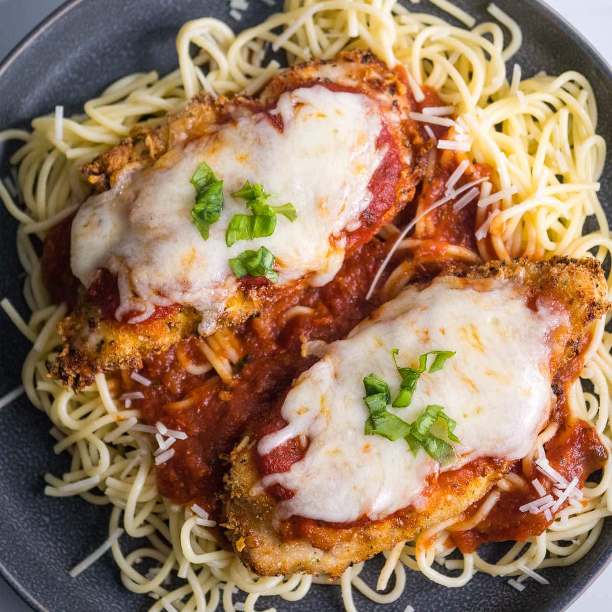 Pieces of chicken on a plate of spaghetti.