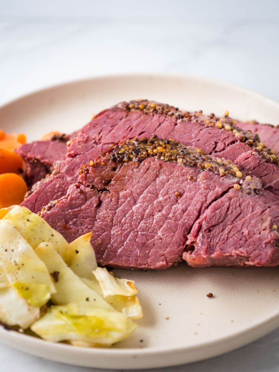 Corned beef cooked in an air fryer served with carrots and cabbage on a plate.