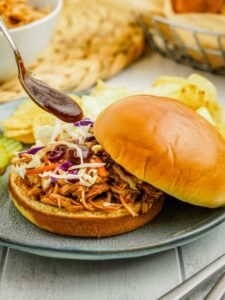 A pulled pork sandwich with coleslaw on a plate.