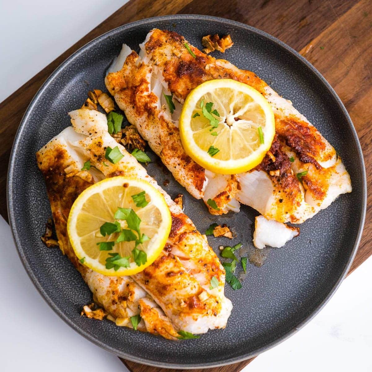 Air fryer cod fillets without breading topped with lemon and herbs.