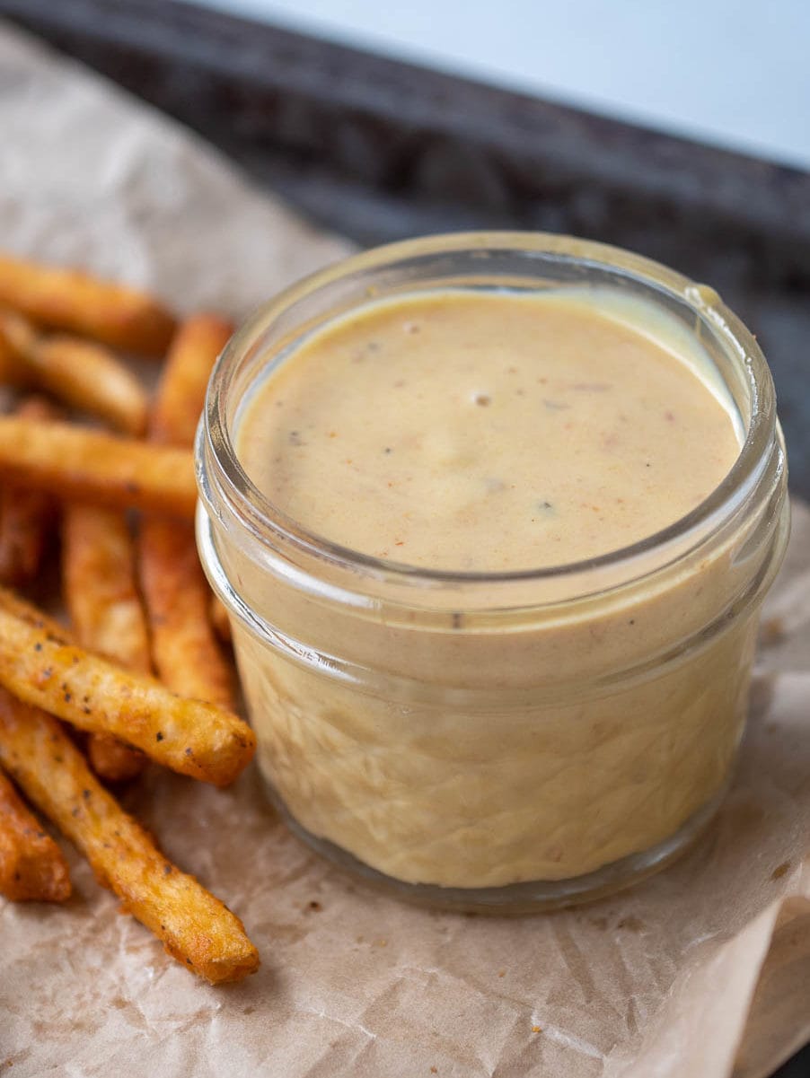 Chick-fil-A sauce in a jar next to French fries