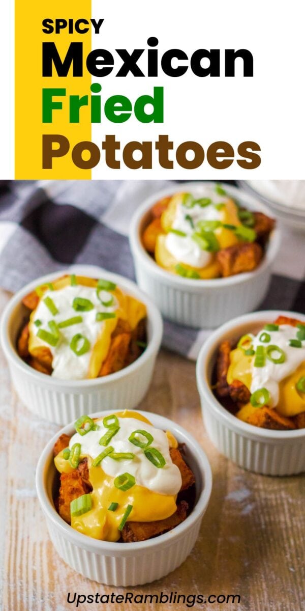 Four ramekins filled with cheesy fiesta potatoes—spicy Mexican fried potatoes topped with melted cheese, sour cream, and chopped green onions—sit on a wooden table.