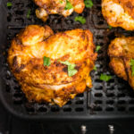 closeup of crispy chicken thigh in air fryer basket