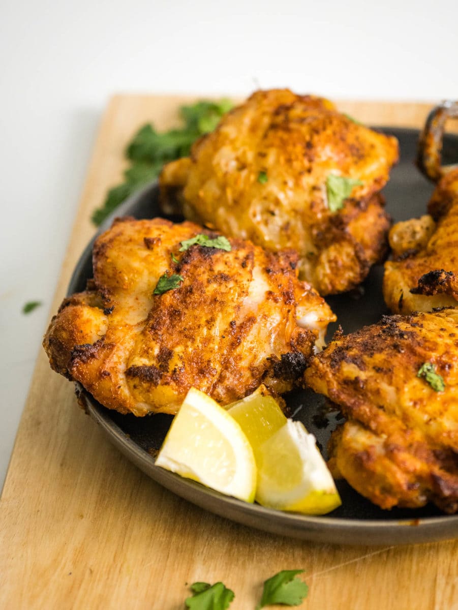 chicken thighs with lemon wedges and fresh herbs