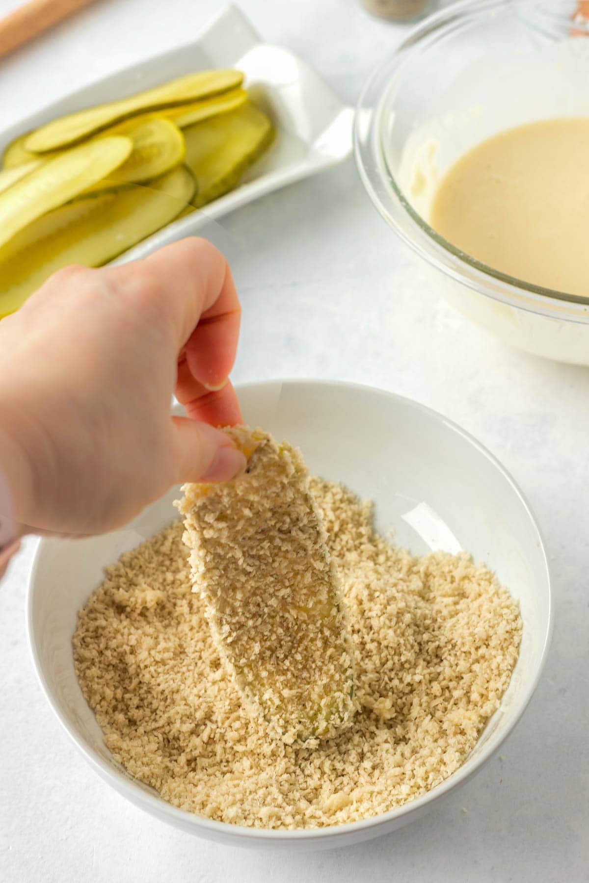 Dipping the pickle in the bread crumb mixture