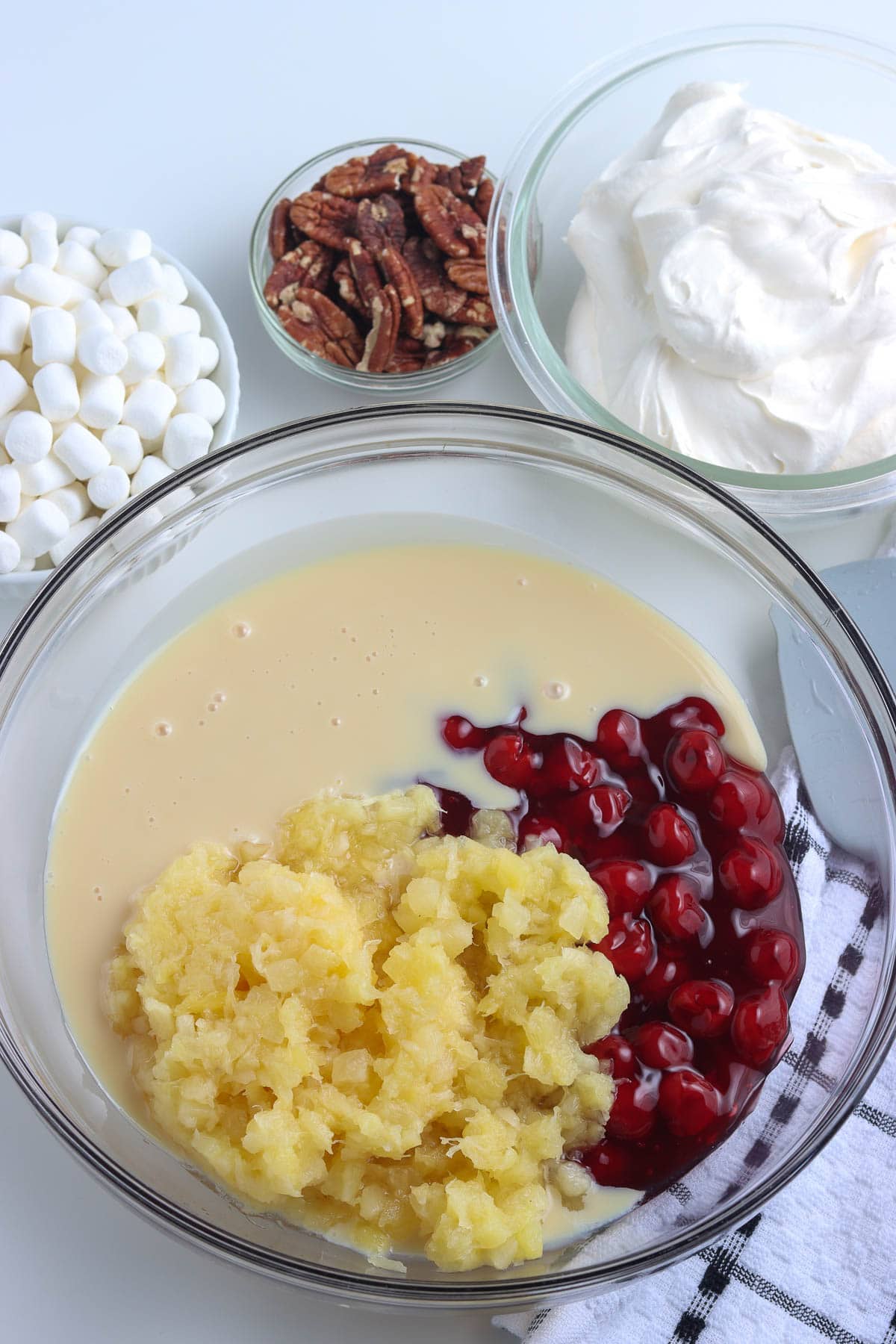 mixing the condensed milk, pineapple and cherries