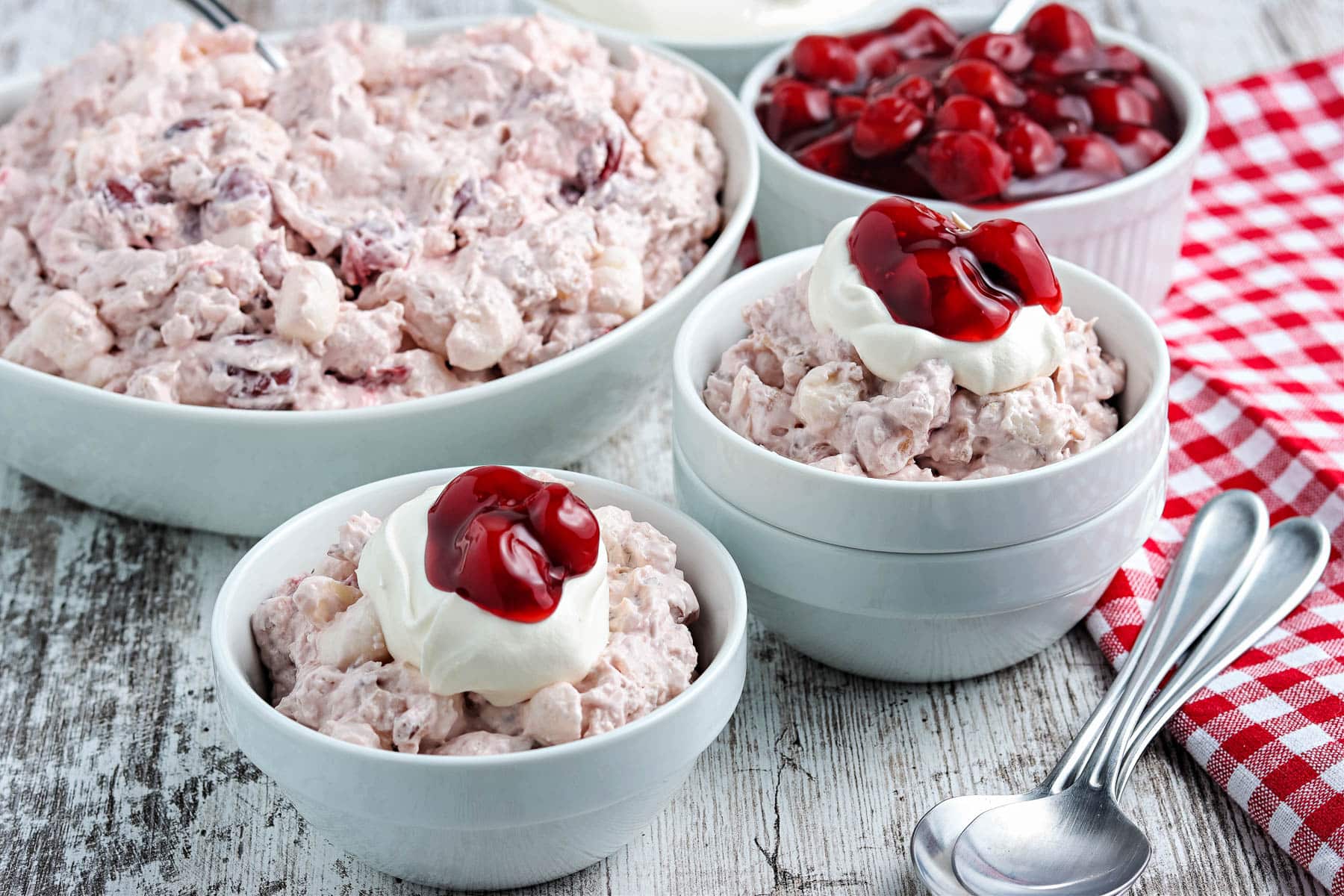 Cherry fluff salad in blue bowls with whipped cream.