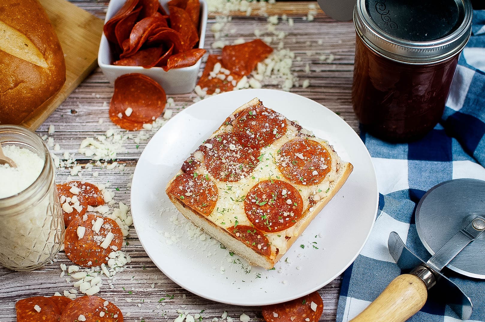 Pepperoni pizza on a plate next to a jar of the best pizza recipes.
