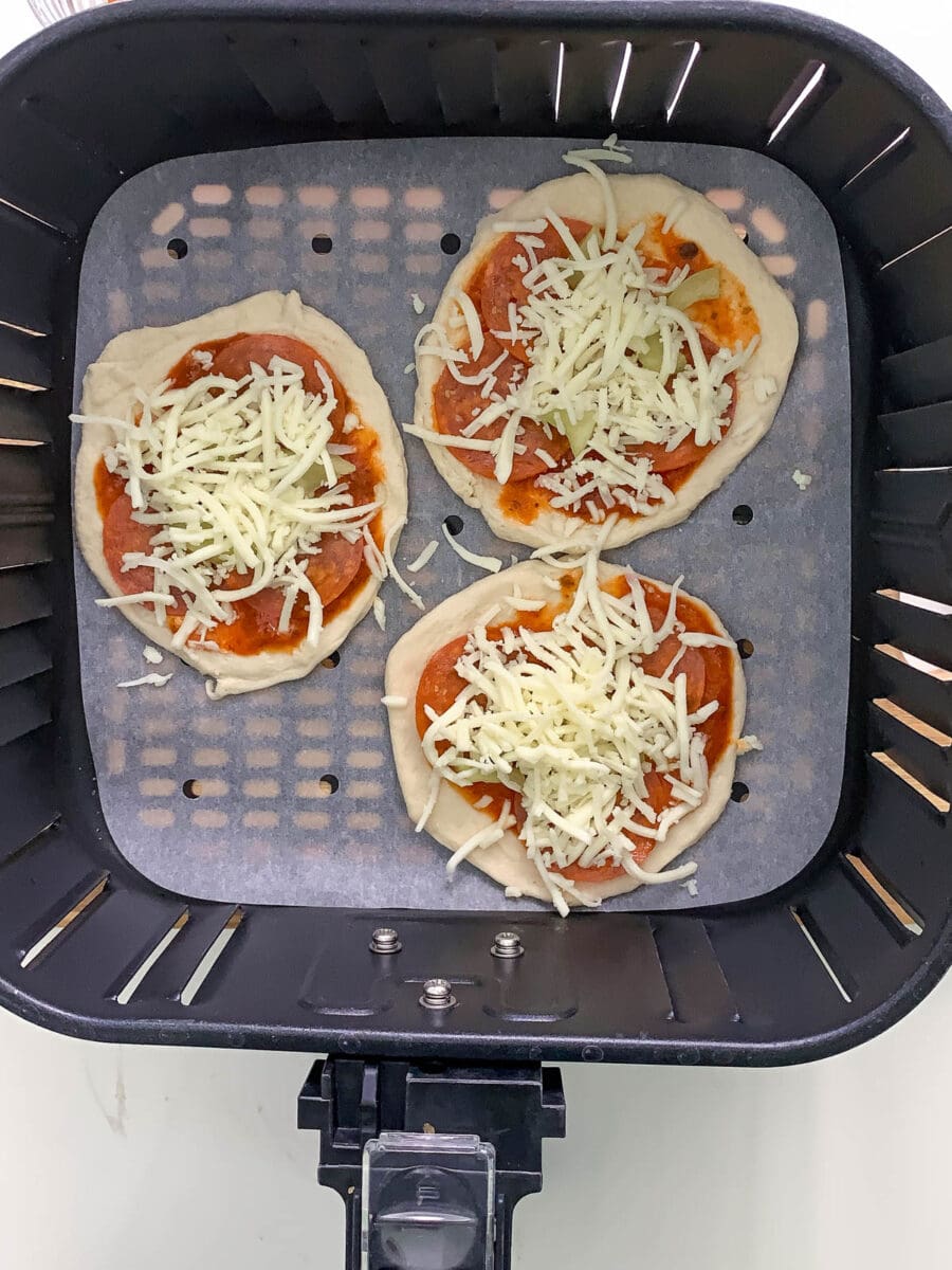 adding cheese to the mini pizza