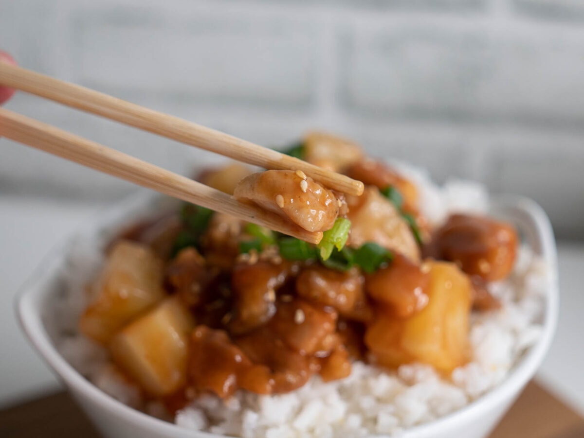 piece of air fryer sweet and sour chicken with chopsticks