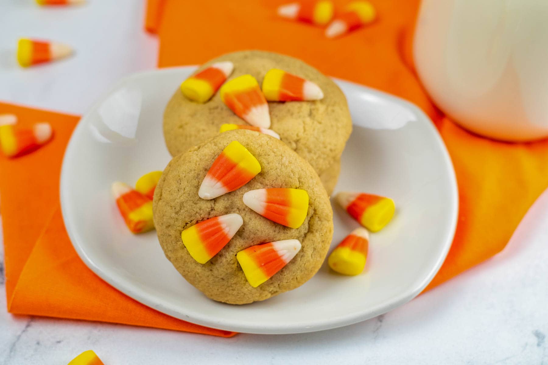 A stack of candy corn cookies on a white plate.